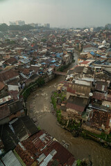 Vertical drone image of high densely populated residential area with dirty river at Bandung City, 2025. West Java, Indonesia.