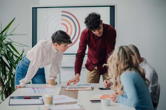 Marketing team analyzing charts and reports during meeting in office