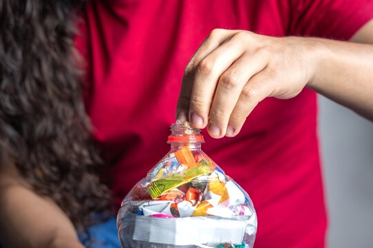Man recycling plastic at home. Plastic bottles filled with packaging. Making 'Bottles of love'. Creando botellas de amor. Ecological bricks. Ecoladrillos