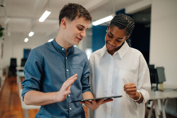 Coworkers using digital tablet, discussing work in office