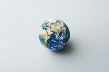 Earth globe with continents, blue oceans, white clouds; depiction of world geography isolated on clean, neutral background