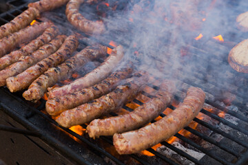 Tasty sausages being cooked on flaming charcoal grill. Meat dishes outdoor..