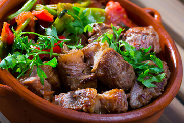 Bulgarian cuisine. Gyuvech - baked meat and vegetable stew served with greens in clay pot