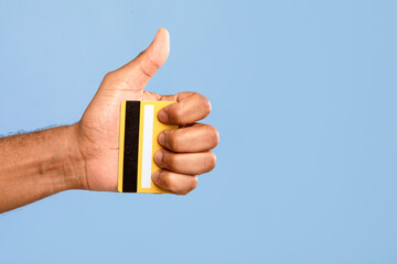 An African American man smiles and shows a thumbs up gesture while holding a yellow credit card in...