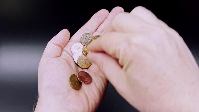 Slow motion POV US caucasian male counting loose change, US coins on dark background
