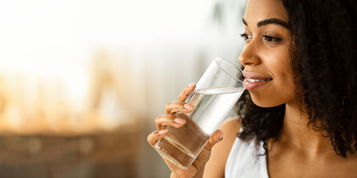 Healthy Liquid. Smiling Black Woman Drinking Water From Glass And Looking Away, Closeup Image With Selective Focus, Copy Space