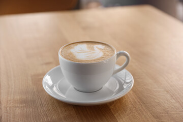 Fototapeta premium Cup of aromatic coffee on wooden table in cafe, closeup
