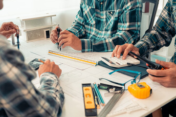 Close-up of industrial engineers team meeting to analyze machinery plans, discuss architectural projects, review construction plans and building plans using tablets at conference table.