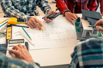 Close-up of industrial engineers team meeting to analyze machinery plans, discuss architectural projects, review construction plans and building plans using tablets at conference table.