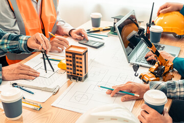 Close-up of industrial engineers team meeting to analyze machinery plans, discuss architectural projects, review construction plans and building plans using tablets at conference table.