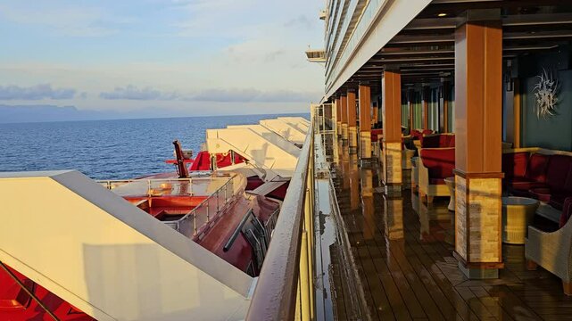MEDITERRANEAN SEA - MAY 25, 2024: Morning sun light side of cruise ship empty of passengers setting it aglow overlooking life boats - peaceful day's beginning