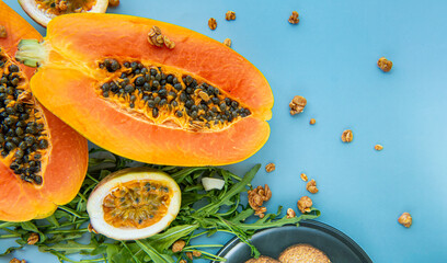 Papaya, passion fruit, rucola and granola on a blue background.