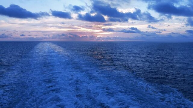 Ship wake-Rich dark blue ocean-clouds-Hint of gold sunrise-