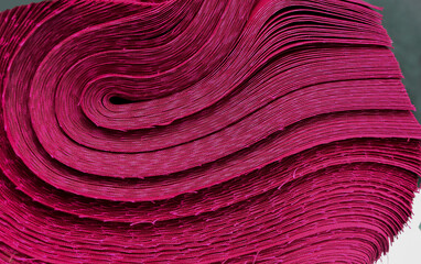 bundle of maroon cotton fabric in industrial space. rough edges cut with messy threads