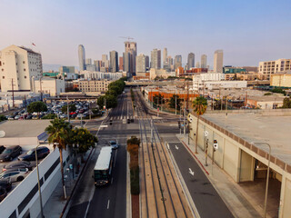 Naklejka premium Los Angeles, USA, cityscape shows a bus driving on a city street with light rail tracks. The skyline is visible in the background, with Bob Hope Patriotic Hall. Historic South Central, USA