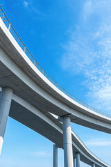 Curved concrete bridge structure under clear blue sky, showcasing modern engineering