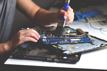 A computer technician is using force to clean the motherboard.