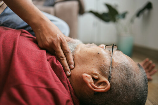 Close Up Of Finger Checking Pulse Of Unconscious Old Man At Home. First Aid