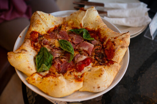Pizza stella napoletana, a traditional star-shaped pizza from Naples or Napoli, Italy. Added with smoked beef, mozzarella, and parmesan cheese, in a cafe environment