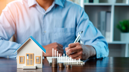 A man is sitting with a calculator and a house model, residential, financial, loan, rental, finance, agreement, estate, property, real, housing.