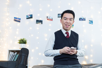 A high school student using his phone in his room