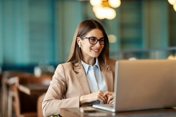 Portrait of cheerful friendly freelancer having online conference call and meeting on laptop from cafe.