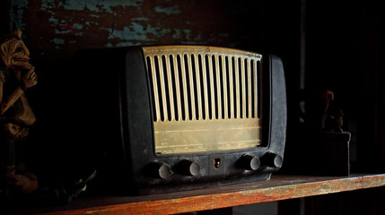 An antique radio with analog controls sits on a wooden shelf