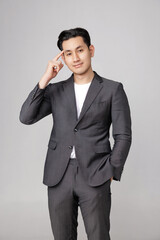 Asian handsome business man in casual gray suit is standing with thinking gesture on isolated studio lighting. Young office worker men.