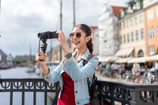 Asian woman traveler use camera record vlog while traveling in the city.