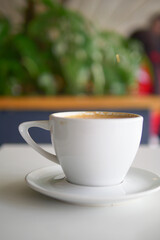Warm cup of coffee on a table surrounded by green plants