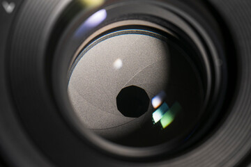 Close-up view of a camera lens diaphragm with visible aperture blades and reflections.