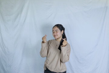 a young girl wearing a gray t-shirt with a cheerful expression and making a love symbol with her fingers. advertising theme concept studio photo