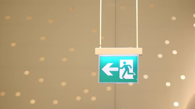 Emergency exit sign points left at a modern building space