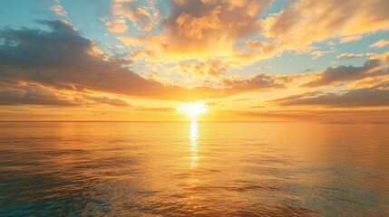 Obraz premium A breathtaking sunrise over a calm ocean with golden reflections on the water.