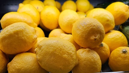 a pile of fresh yellow lemons on the shelf in a supermarket
