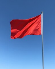 Vivid red flag waving against a clear blue sky symbolizing warning danger alert signal caution and safety