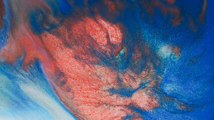 Shiny emulsion. Sparkling liquid. Defocused blue red crimson colorful paint in water glitter fluid stream pouring on abstract background.