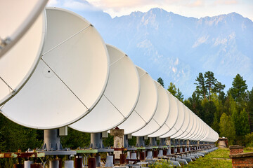 A row of radio telescope dishes against the background of mountains