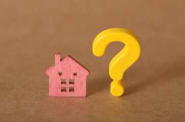 Real Estate Decision Concept: Wooden House Cutout with Yellow Question Mark