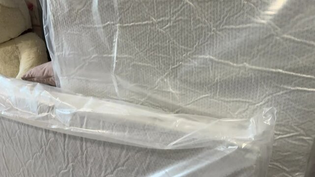 Cardboard packages with panels for assembling an ottoman. Nearby are orthopedic mattresses in packaging.
