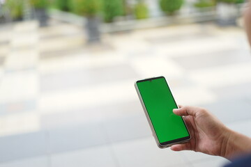 green screen mockup of mobile phone. hand holding texting using mobile phone at outdoors. with blur background. people work contact marketing business,technology,chatting,shopping online,using mobile.