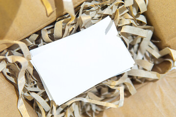 After opening the box, a textured white business card was revealed, resting on irregularly torn...