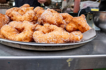 Freshly fried sfinj donuts covered in sugar, a popular North African and Jewish treat often enjoyed after Passover during the Mimouna celebration.