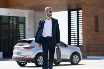 Mature business man in suit outdoors. Rich businessman next to a luxury car. Global business. Successful business. Elegant business man in front of expensive car. Successful businessman.