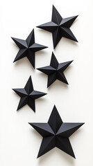 Obraz premium Large bold star silhouettes, cut from black paper, contrasting sharply against a bright white background.