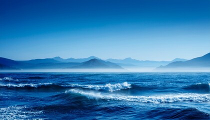 Obraz premium misty blue coastal landscape with waves and distant mountains