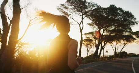 Woman, fitness and running with sunset on mountain road for workout, exercise or cardio training. Back view, female person or runner with sunshine on street for sprint, race or challenge in nature