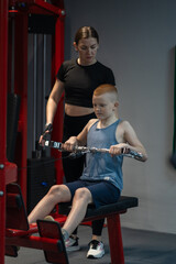 Teenager exercising on Multi-gym machine. Weight lifting exercises in the gym.