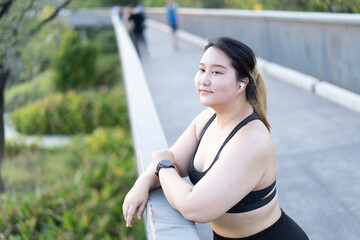 Portrait of A woman leans on a railing in a park, showcasing a relaxed demeanor while others walk...