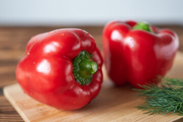 Red bell pepper on a cutting board with dill and parsley